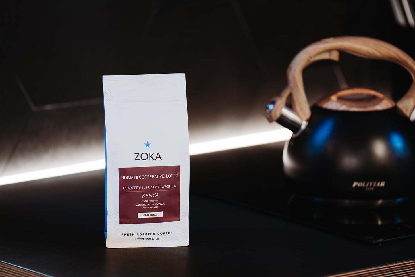 Bag of Kenya peaberry coffee sits on stove top next to tea pot