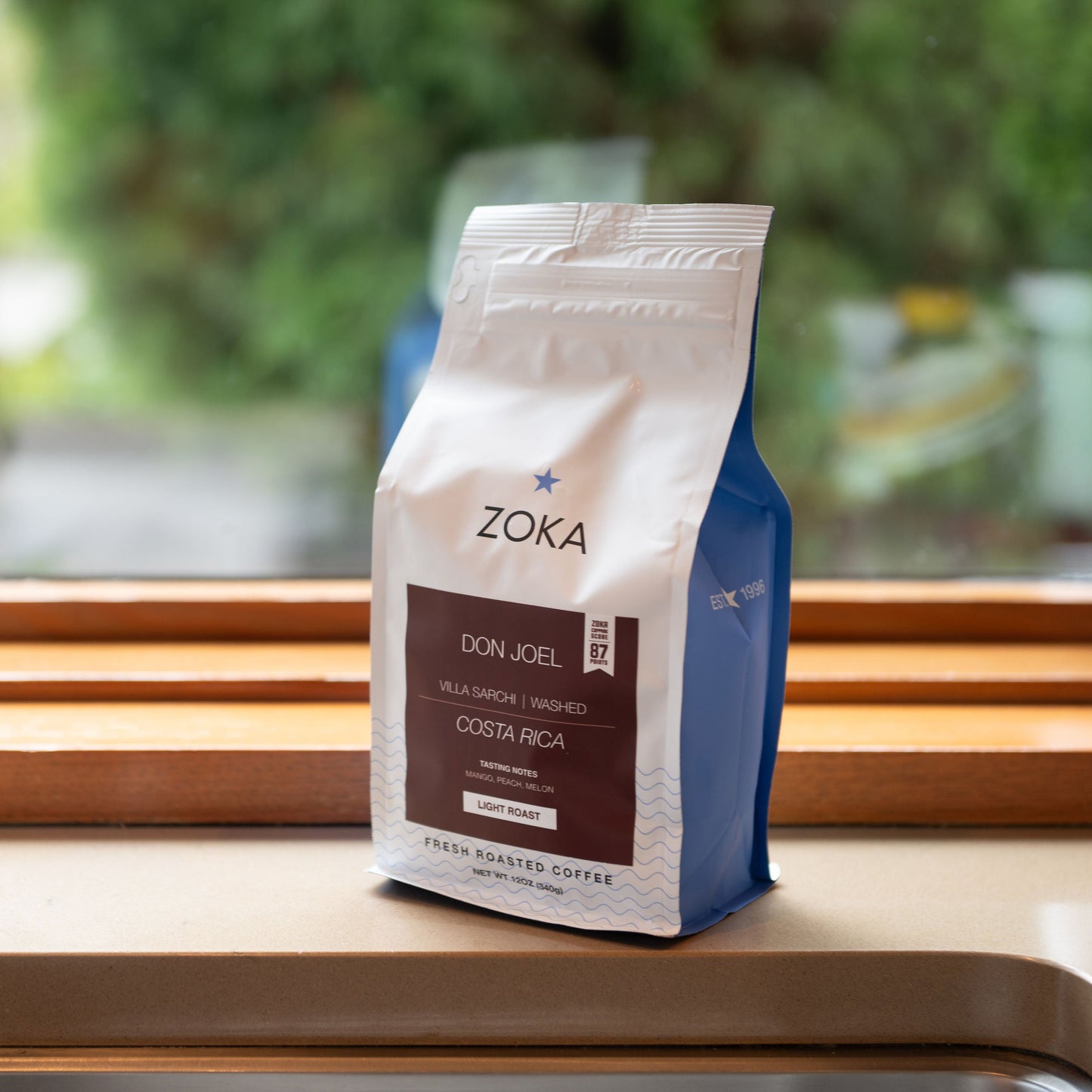 Zoka coffee bag on a windowsill with a blurred outdoor background