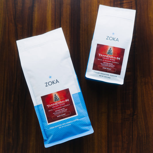 Two Zoka Tannenbaum coffee packages, one 12 oz, one 2 pound, on a wooden surface